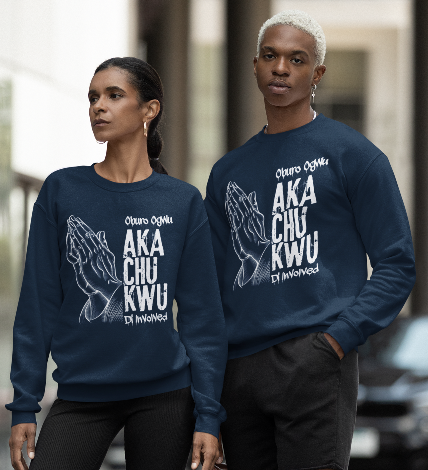 Two people wearing matching navy blue sweatshirts with white text on a city street.