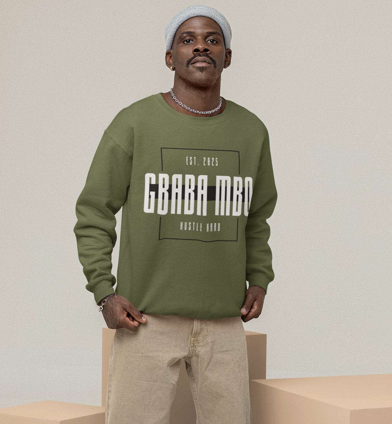 Man wearing a green sweatshirt with text, standing on beige cubes against a plain background