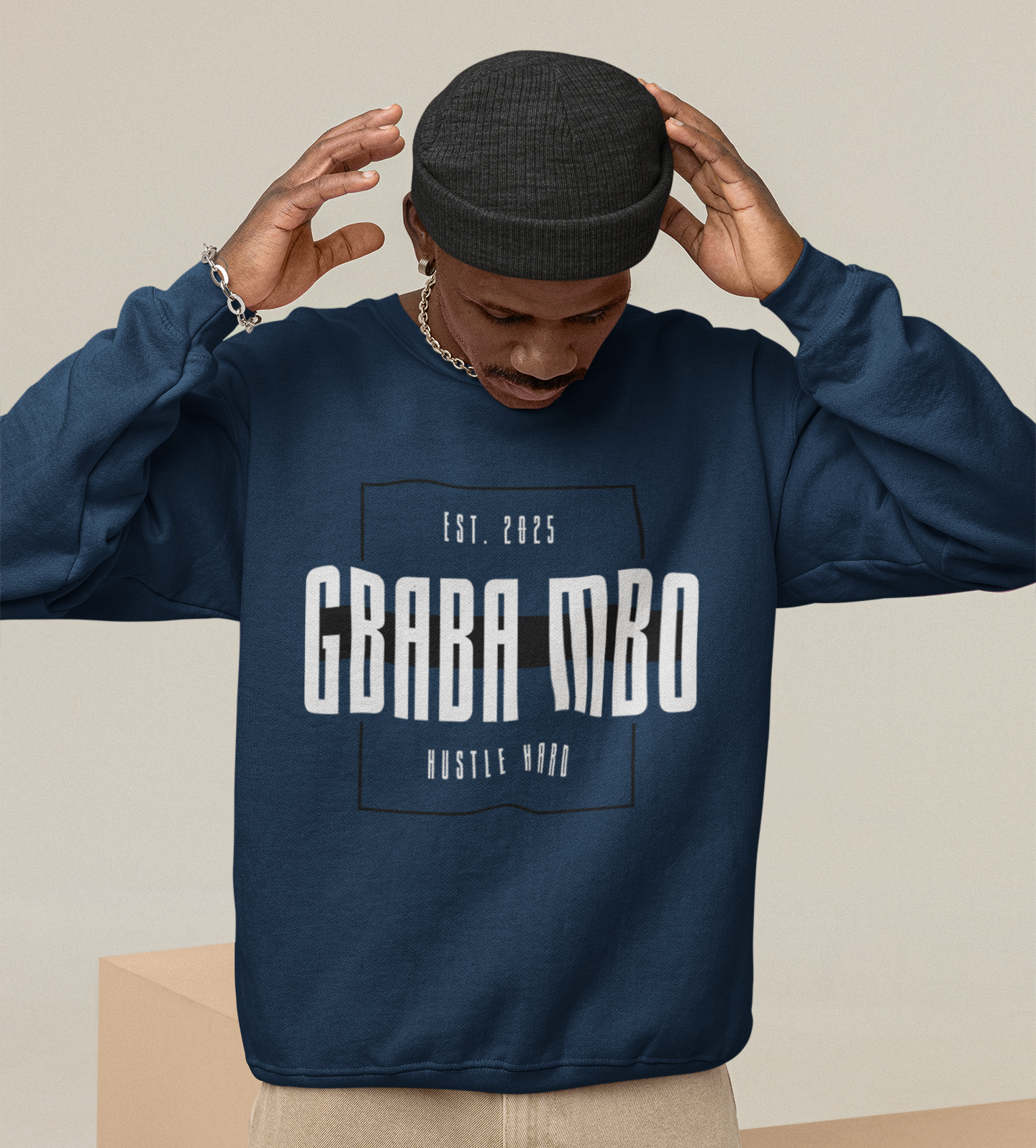 Person wearing a navy blue sweatshirt with text, standing on beige geometric blocks.