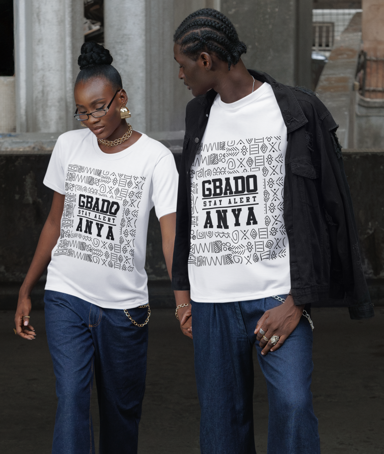 Two people wearing matching white t-shirts with text and blue jeans standing on a concrete surface.