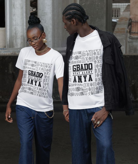Two people wearing matching white t-shirts with text and blue jeans standing on a concrete surface.