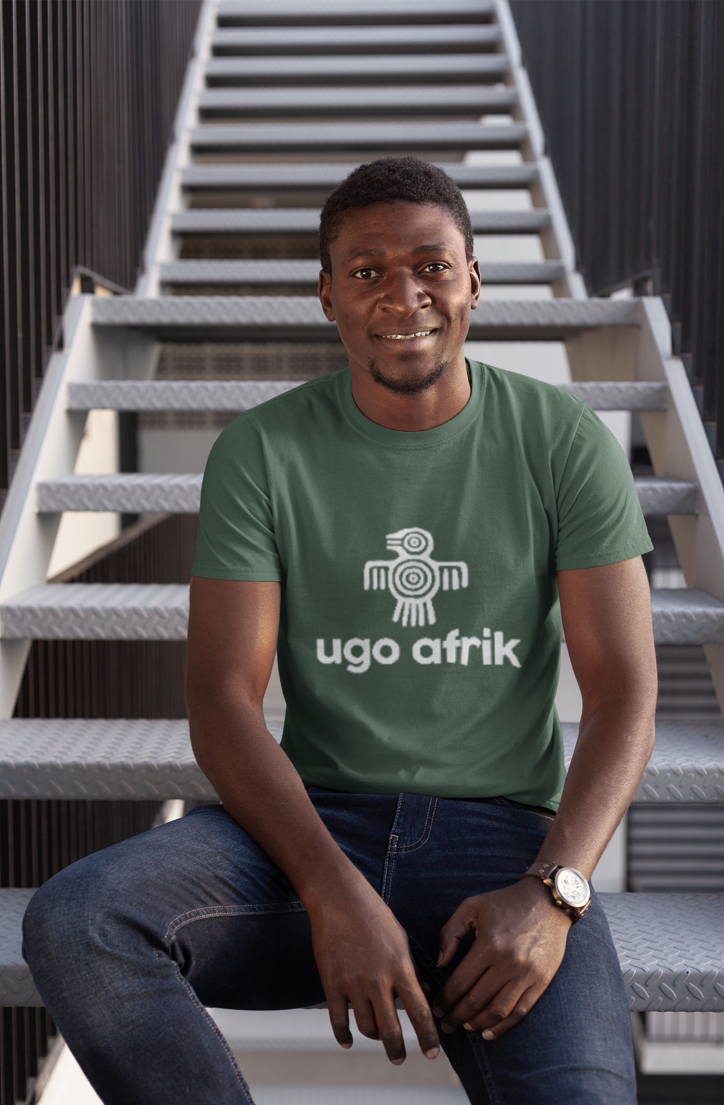 Man wearing a green t-shirt with 'ugo afrik' logo sitting on stairs.