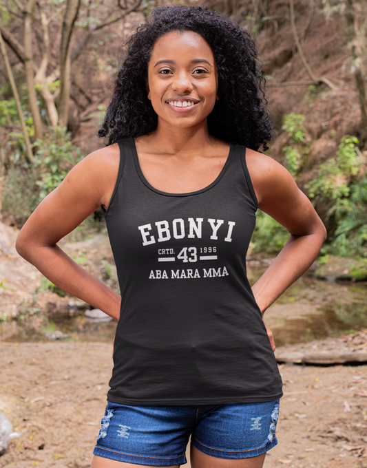 Woman wearing a black tank top with 'EBONYI' text, standing in a forest setting.