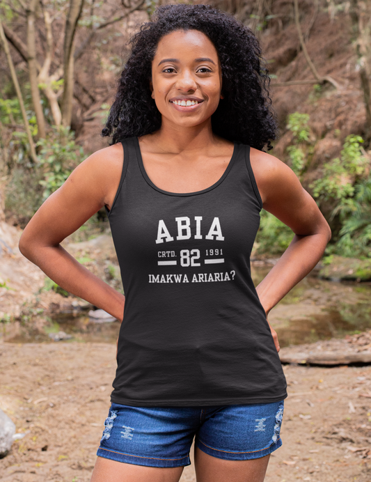 Woman wearing a black tank top with text standing in a forest setting